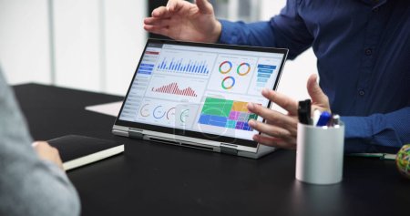 Zwei Geschäftsleute analysieren Finanzgrafik am Laptop