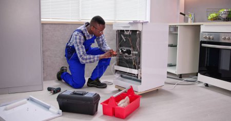 Photo for African Repairman Repairing Dishwasher Appliance. Electrical Check - Royalty Free Image
