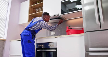 Téléchargez les photos : Jeune réparateur réparant le filtre d'extracteur de cuisine dans la salle de cuisine - en image libre de droit