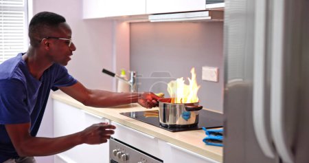 Téléchargez les photos : Cuisine cuisine erreur de cuisson et incendie désastre. Homme choqué - en image libre de droit