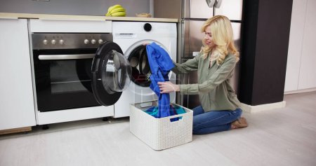 Foto de Mujer cargando ropa sucia en la lavadora para lavar en el lavadero - Imagen libre de derechos