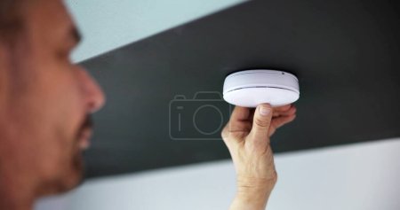 Téléchargez les photos : La main de la personne installant le détecteur de fumée sur le mur de plafond à la maison - en image libre de droit