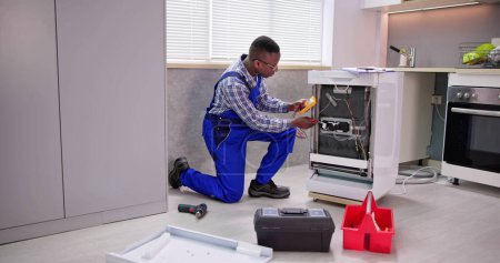 Foto de Africano americano reparador fijación de lavavajillas máquina de electrodomésticos - Imagen libre de derechos