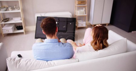 Photo for Man Sitting On Sofa In Front Fallen Television With Broken Screen - Royalty Free Image