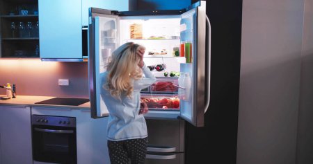 Photo for Hungry Woman At Night With Open Fridge - Royalty Free Image