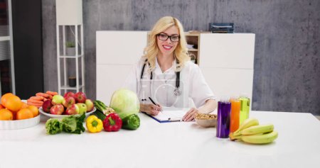 Photo for Portrait Of Female Dietician With Vegetables On Desk - Royalty Free Image