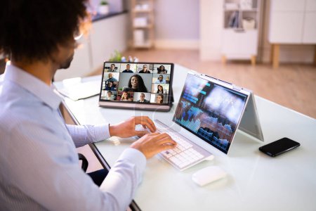 Téléchargez les photos : Regarder une réunion de vidéoconférence en ligne au bureau - en image libre de droit