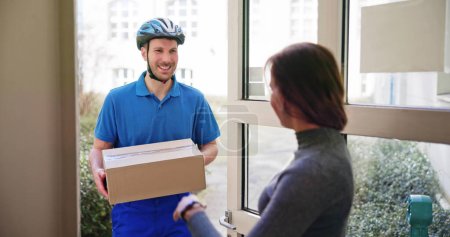 Photo for Happy Young Woman Accepting Parcel Box From Delivery Man - Royalty Free Image