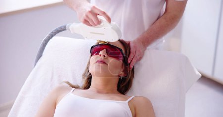 Téléchargez les photos : Esthéticienne donnant traitement laser épilation sur le visage de la femme - en image libre de droit