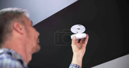Foto de La mano de la persona instalando el detector de humo en la pared del techo en el hogar - Imagen libre de derechos