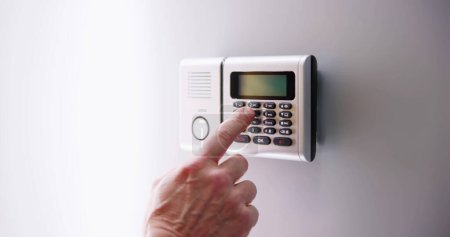 Photo for Security Alarm Keypad With Person Arming The System - Royalty Free Image