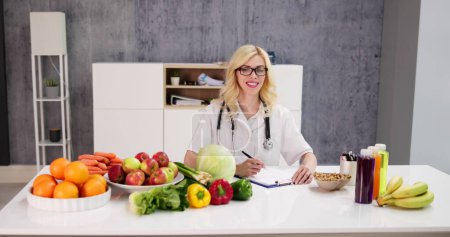 Téléchargez les photos : Portrait de diététicienne avec légumes sur le bureau - en image libre de droit