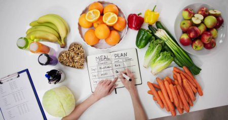 Foto de Médico dietista mujer escribiendo plan de comidas en objetivos - Imagen libre de derechos