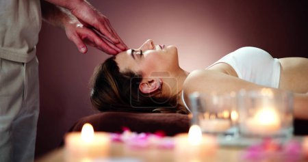 Mujer joven recibiendo masaje en la cabeza en spa de belleza
