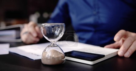Photo for Hourglass On Desk. Running Late With Invoice Or Bill - Royalty Free Image
