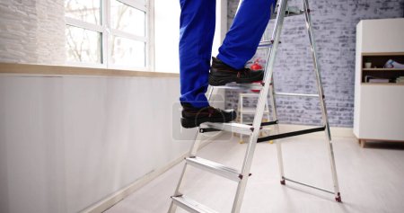 Photo for Man Climbing Step Ladder In Safety Shoes - Royalty Free Image