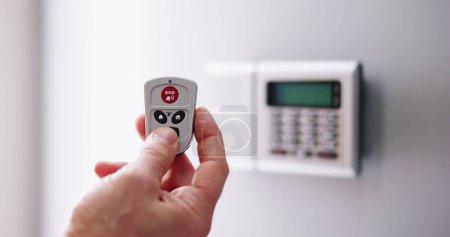 Photo for Security Alarm Keypad With Person Arming The System With Remote Controller - Royalty Free Image