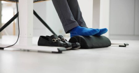 Mann verwendet Fußstütze, um Rückenbelastung und Ermüdung der Füße zu verringern