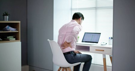 Téléchargez les photos : Douleur au dos Mauvaise posture Homme assis au bureau - en image libre de droit