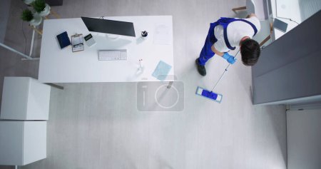 Photo for Janitor Cleaning White Desk In Modern Office - Royalty Free Image