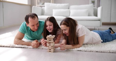 Téléchargez les photos : Famille heureuse posant sur le tapis jouant avec les blocs en bois à la maison - en image libre de droit