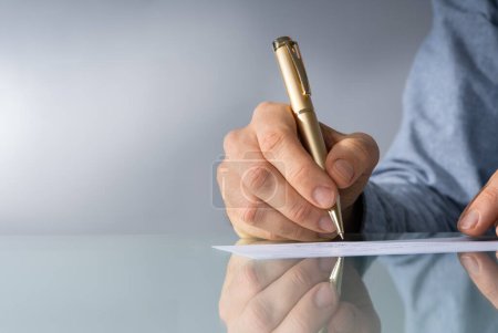 Photo for A Male Hand Filling Out The Amount On A Cheque - Royalty Free Image