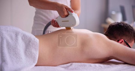 Téléchargez les photos : Procédure de cosmétologie d'épilation d'un thérapeute à une clinique de beauté cosmétique - en image libre de droit