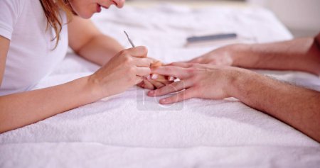 Téléchargez les photos : Esthéticienne manucure ongle buff de l'homme dans spa - en image libre de droit