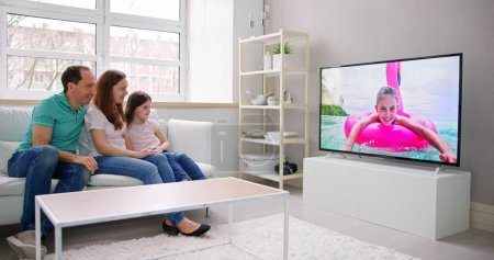 Foto de Joven familia viendo televisión juntos en casa - Imagen libre de derechos