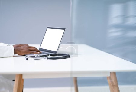 Téléchargez les photos : Midsection du médecin masculin utilisant l'ordinateur portable au bureau dans la clinique - en image libre de droit