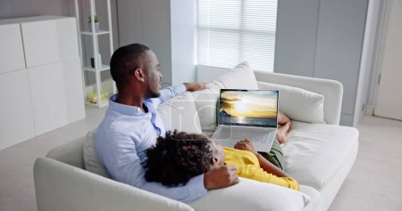 Téléchargez les photos : Famille africaine Regarder un film de télévision sur ordinateur portable - en image libre de droit