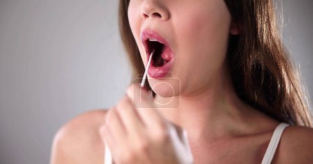 Foto de La mano del dentista toma la prueba de saliva de la boca de la mujer con algodón Swab - Imagen libre de derechos
