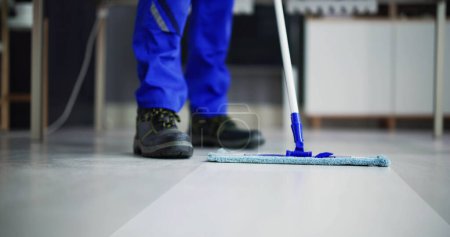 Foto de Retrato de feliz conserje masculino piso de limpieza en la oficina - Imagen libre de derechos