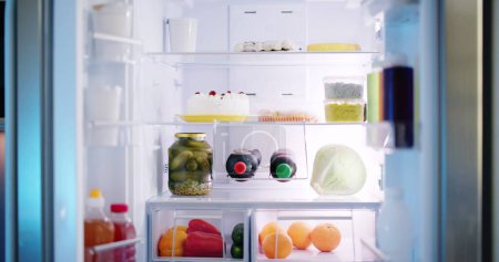 Téléchargez les photos : Réfrigérateur ouvert plein de jus et légumes frais dans la cuisine - en image libre de droit