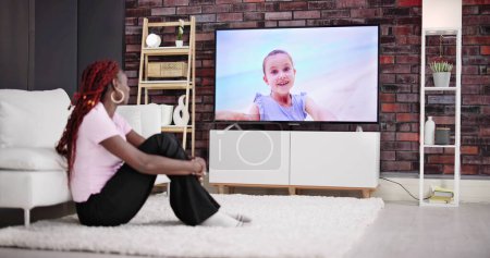 Photo for Young Woman Sitting On Carpet Watching Movie On Television At Home - Royalty Free Image