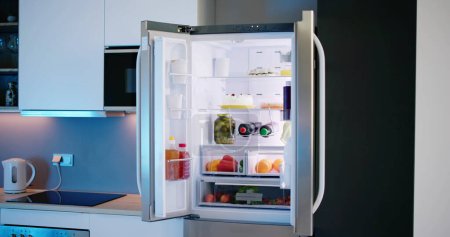 Réfrigérateur ouvert plein de jus et légumes frais dans la cuisine

