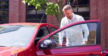 Téléchargez les photos : Jeune homme avec des béquilles ouverture porte d'une voiture rouge - en image libre de droit