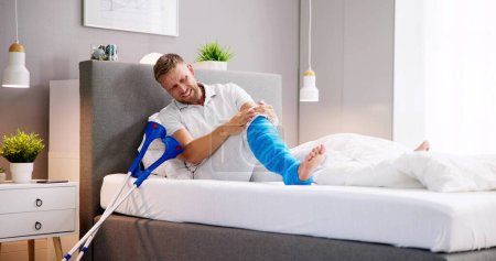 Foto de Hombre con lesión de fractura de pierna rota y molde usando muletas - Imagen libre de derechos