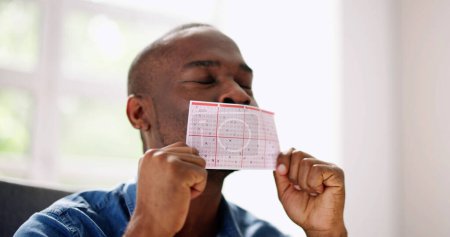 Téléchargez les photos : African Man Kissing Gamble Ticket. Lotto Jeu de cartes - en image libre de droit