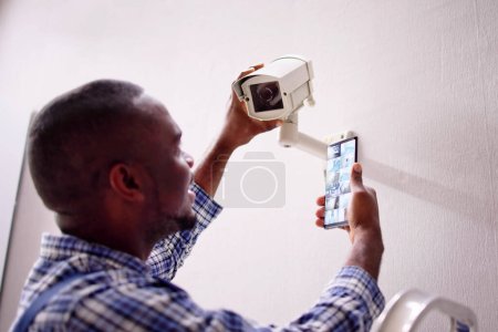 Téléchargez les photos : Afro-Américain utilisant la sécurité et le système d'alarme sur téléphone mobile - en image libre de droit