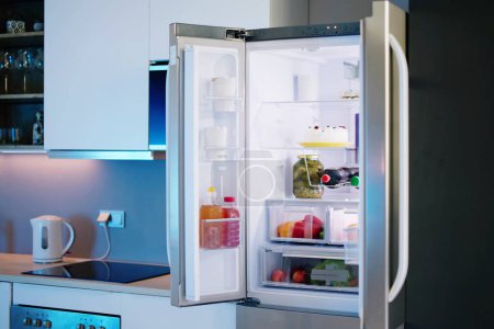 Téléchargez les photos : Réfrigérateur ouvert plein de jus et légumes frais dans la cuisine - en image libre de droit
