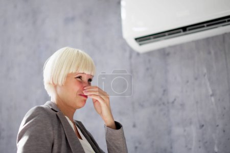 Foto de Mujer cubriendo su nariz de mal olor dentro de AC - Imagen libre de derechos