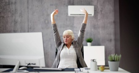 Téléchargez les photos : Femme d'affaires détendue bénéficiant du refroidissement du climatiseur dans le bureau - en image libre de droit