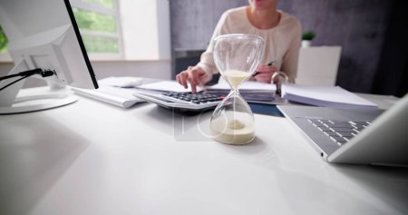 Photo for Late Invoice And Billing Deadline With Hourglass At Desk - Royalty Free Image