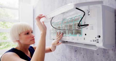 Photo for Young Woman Cleaning Air Conditioning System At Home - Royalty Free Image