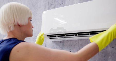 Photo for Young Woman Cleaning Air Conditioning System At Home - Royalty Free Image