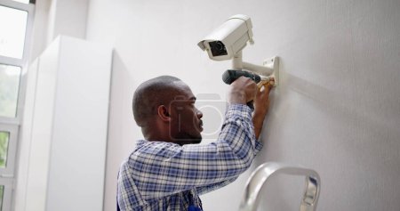 Téléchargez les photos : Gros plan du technicien ajustant la caméra cctv sur le mur - en image libre de droit