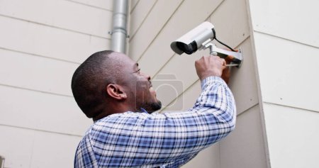Téléchargez les photos : Afro-américain bricoleur avec caméra de vidéosurveillance, système de sécurité - en image libre de droit