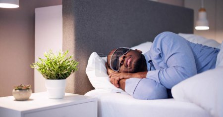 Téléchargez les photos : Jeune homme africain dormant avec masque de sommeil - en image libre de droit