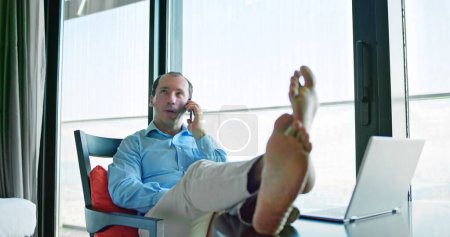 Téléchargez les photos : Relaxé jeune homme d'affaires assis pieds vers le haut au bureau - en image libre de droit